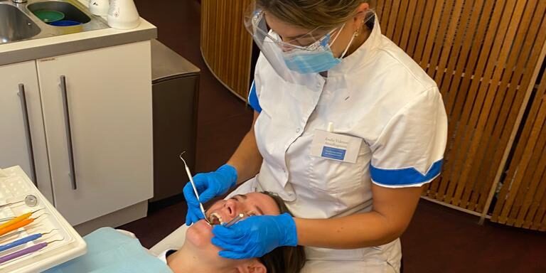 Mondhygiëniste Emilie helpt een patiënt bij het behandelen van Tandsteen