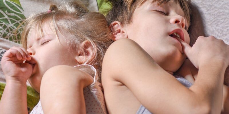 Broer en zus slapen en doen aan duim- of vingerzuigen in bed