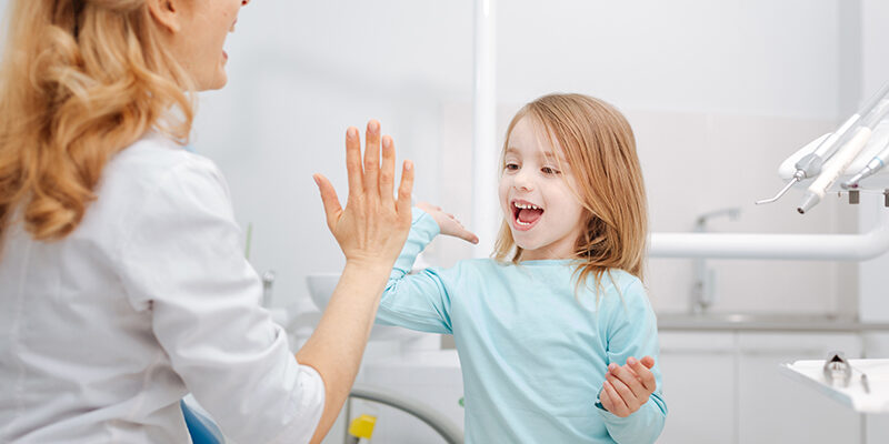 Meisje geeft op jonge leeftijd een high five aan de tandarts