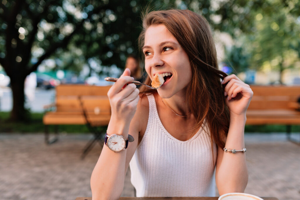 Vrouw in een wit shirt neemt een hap van haar eten en doet aan Goed kauwen voor een gezond gebit
